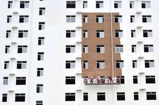Workers paint the exterior of an unfinished residential building in Xiangfan, Hubei province