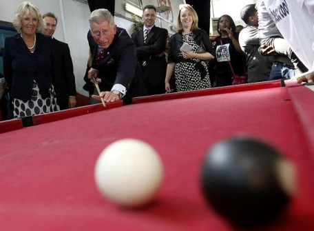 Britain’s Camilla, Duchess of Cornwall watches her husband Prince Charles play pool with children during their visit to the Kids Company in Camberwell, London