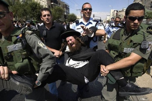An ultra-Orthodox Jew is detained by Israeli police and border police officers during a protest in Jerusalem