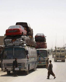 Passenger buses are loaded with cars for transport in Kandahar
