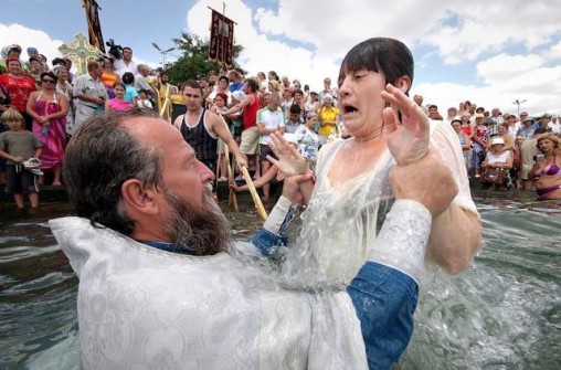 An Orthodox priest baptises a woman during the celebration of the christening of the country in the Ukrainain Black Sea city of Sevastopol