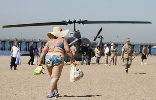 A woman walks on the beach at Coney Island past an AH-1 Cobra helicopter in New York