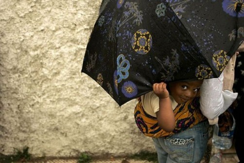 A child peeps from under an umbrella during a protest in Rabat