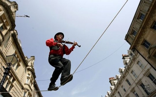 A street performer walks a tightrope and plays a violin during the Brighton Festival 2009 in Brighton southern England