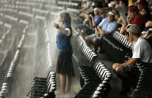 Girl runs into water pouring down from stadium’s upper balcony during a rain delay  in Arlington